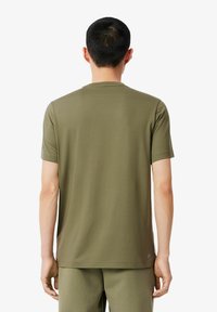 Tricou verde măslin cu mâneci scurte dintr-un material ușor și fin, cu guler tip crew și fără modele sau accente vizibile.