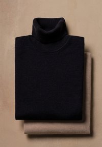 Suéter preto de gola alta dobrado em cima de um suéter bege. Ambos feitos de um tecido de malha macio, apresentando um design limpo e minimalista.