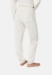 Jogging en coton blanc avec une poche arrière, une taille élastique et des chevilles resserrées. Texture douce avec une finition lisse.