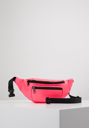 Jasnoróżowa nerka z dwoma czarnymi kieszeniami zapinanymi na zamek i regulowanym czarnym paskiem z klamrą na białej powierzchni.