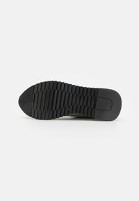 Black rubber shoe sole with ridged tread pattern, flat heel, and rounded toe. Designed for traction and stability.