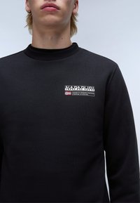 Zwarte sweatshirt met een gestructureerde afwerking, met een logo op de borst in witte tekst en een klein Noors vlagdetail. Geribbelde kraag.