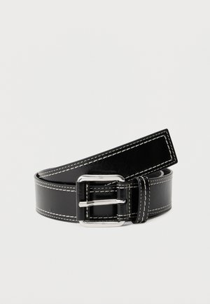 Černý kožený pásek s bílým prošíváním a stříbrnou obdélníkovou přezkou, stočený na jednobarevném světlém pozadí.