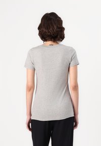 Tricou gri cu mânecă scurtă, fabricat dintr-un material moale și ușor. Are un guler rotund și o croială ajustată, cu o textură fină și detalii minime.