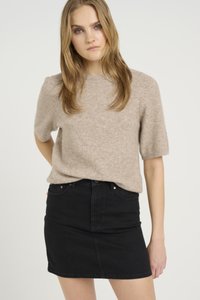 Beige strikkegenser med korte ermer, kombinert med et sort denim miniskjørt. Genseren har en myk tekstur og rund hals.