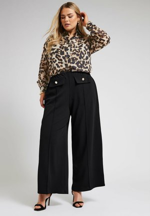 Blouse met luipaardprint en kraag, lange mouwen, gecombineerd met hoge, wijde zwarte broeken met frontzakken en metallic accenten.