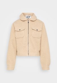 Beige cropped jakke lavet af tekstureret stof, med lynlås foran, to brystlommer med klapper og en rund krave.