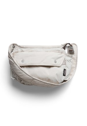 Light beige crossbody bag with adjustable strap, front flap pocket secured by two snap buttons, and small black brand label on the side.