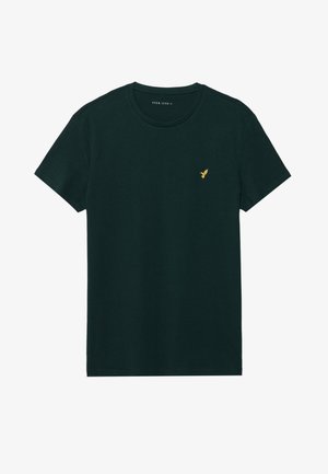 T-shirt en coton vert foncé avec un col rond, des manches courtes et un petit logo doré d'oiseau sur la poitrine gauche. Texture lisse et coupe classique.