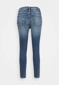 Vista trasera de unos jeans de mezclilla azul de corte ajustado con un lavado desvanecido y dos bolsillos traseros, logo de Calvin Klein en la cinturilla.