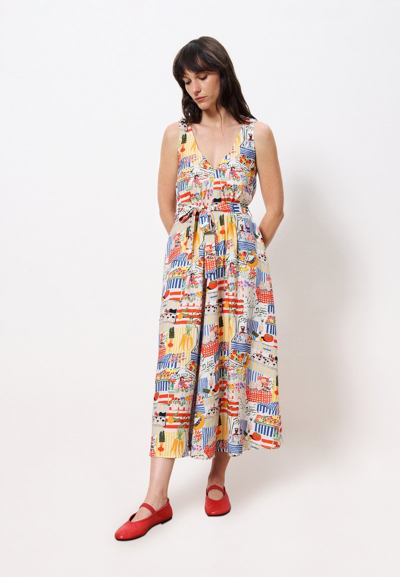 Robes maxi colorées et à motifs avec un décolleté en V, sans manches, taille cintrée et poches. Associée à des chaussures plates rouges.