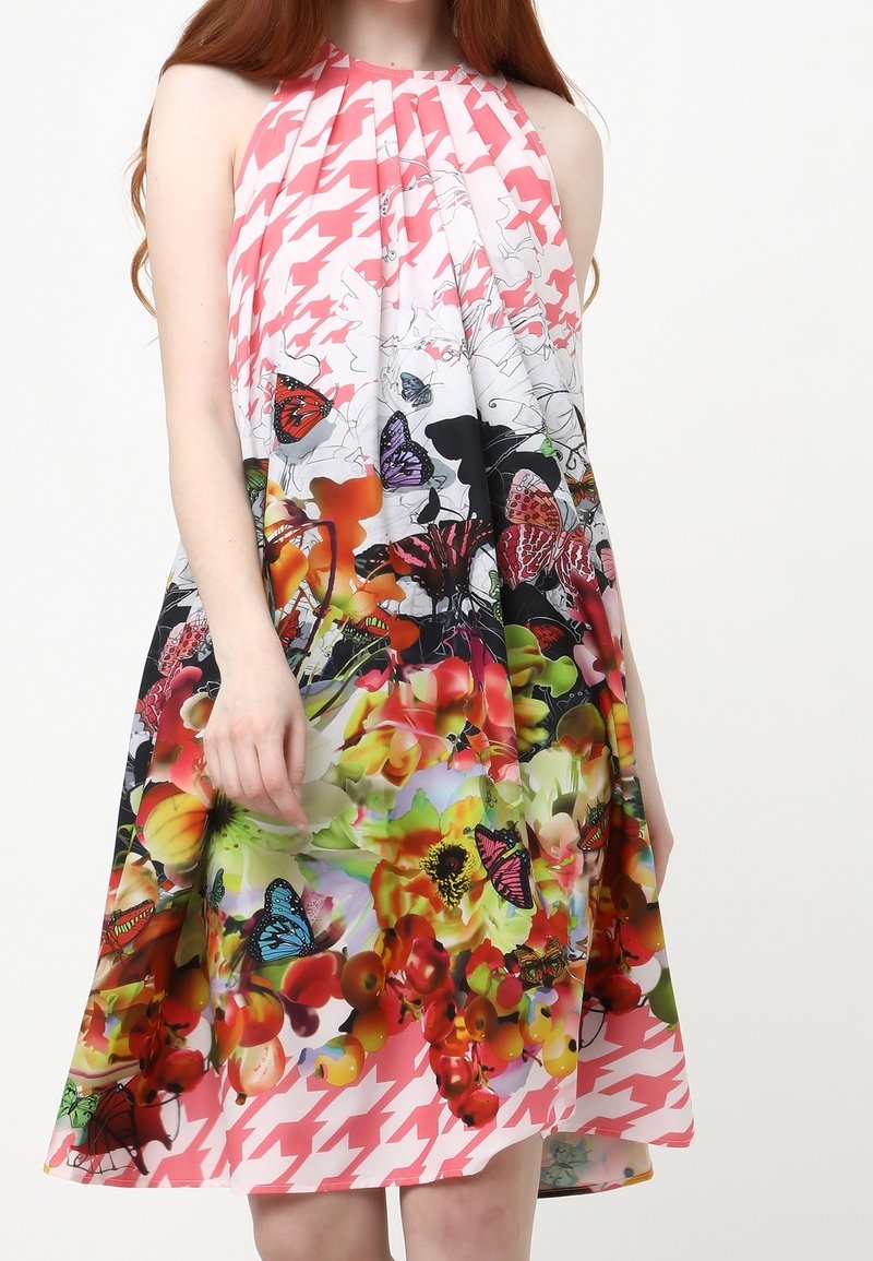 Robe dos nu à motif floral avec des papillons et des fleurs vives dans des tons de rose, vert et orange. Tissu léger avec un design plissé.