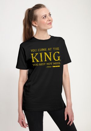 Sort bomulds T-shirt med gule bogstaver, der står "DU KOMMER EFTER KONGEN, DU BEDSTE IKKE MISSE. -Omar THE WIRE" i fed, slidt stil.