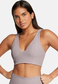 Top corto de canalé en color lila con un escote en V profundo, tirantes anchos y un diseño ajustado. La textura es suave y elástica, ideal para ropa deportiva.
