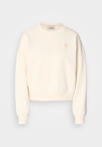 Sweatshirt court crème avec un col rond, des poignets côtelés et un logo brodé discret sur la poitrine. Tissu à la texture douce.