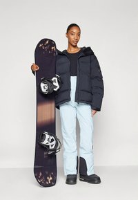 Black puffer jacket, light blue snow pants, snowboard with bindings, and black boots. Smooth material with varied textures and color gradients.