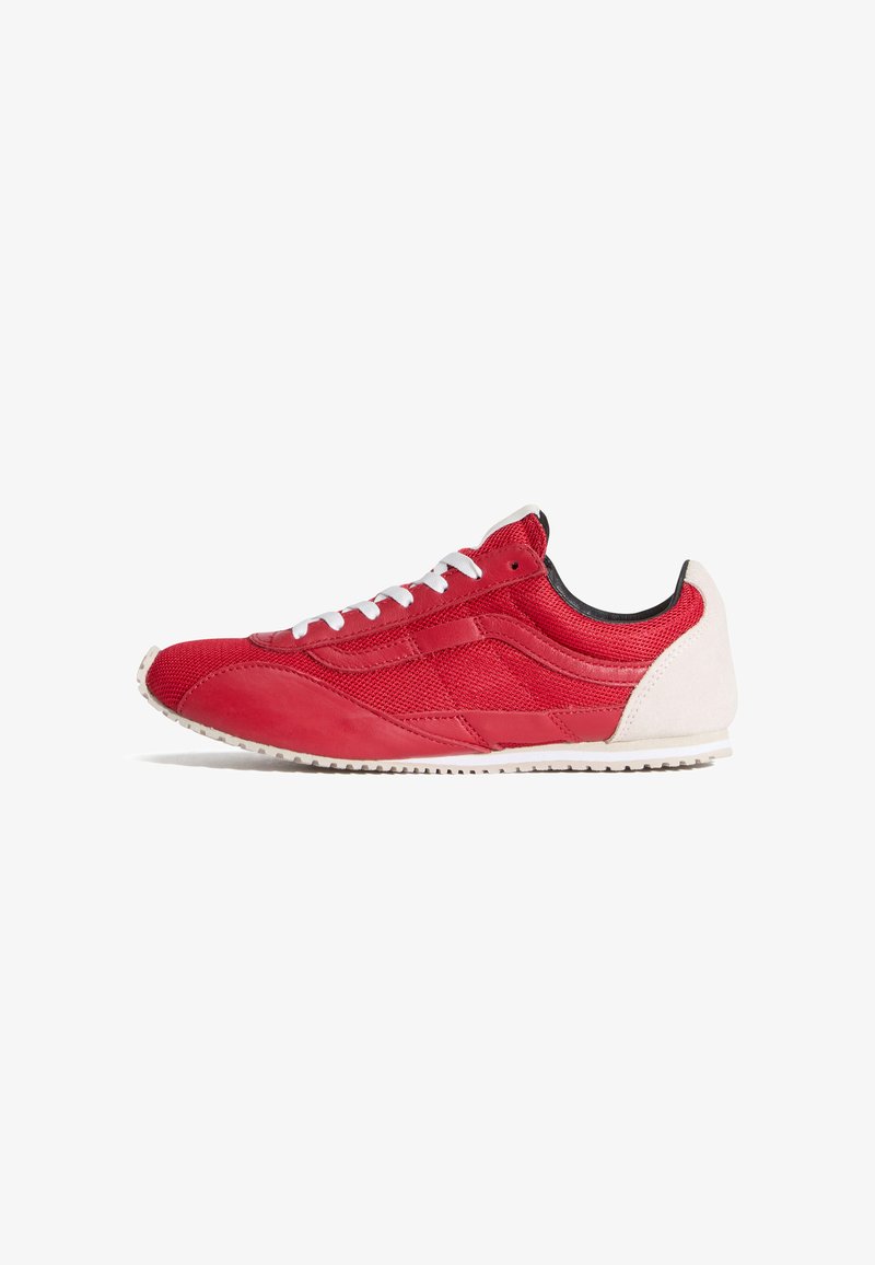 Chaussure de sport rouge en mesh et cuir, avec une semelle en caoutchouc blanche, des lacets blancs et un talon de couleur claire contrastante.
