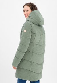 Manteau en duvet matelassé vert avec capuche, doté d'un tissu texturé, de coutures diagonales et d'un patch logo circulaire sur la manche.