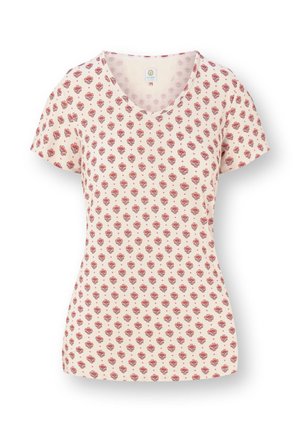 Cream short-sleeve V-neck shirt with repeating red floral pattern, fitted waist, and soft fabric texture.