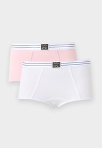 Deux boxers pour femmes, un blanc et un rose clair, chacun avec une ceinture blanche présentant des rayures noires et une étiquette noire centrale.