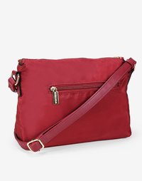 Bolso cruzado rojo de nylon con textura suave, correa ajustable, bolsillo frontal con cremallera y detalles en metal dorado.