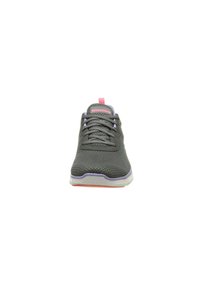 Zapatilla deportiva gris con parte superior de malla, acentos morados y lengüeta de talón rosa. Cuenta con cordones grises y suela blanca con detalle naranja.