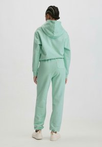 Mintgrünes Hoodie- und Jogginghosen-Set aus weichem Material. Das Hoodie hat eine verstellbare Kapuze; die Hose verfügt über einen elastischen Bund und einen gerippten Saum.