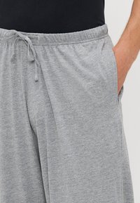 Pantalones de chándal grises de algodón con cinturilla elástica, cierre con cordón y bolsillos laterales, que presentan una tela suave y texturizada.
