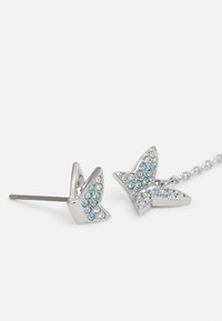 Silverfärgade fjärilshängsörhängen prydda med blå och klara rhinstenar, med en stiftdesign och en kedja som kopplar samman de två delarna.