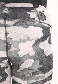Legginsy Reebok z czarno-białym wzorem kamuflażu, z teksturowanymi detalami i dopasowanym krojem. Rozciągliwy materiał zwiększa komfort.