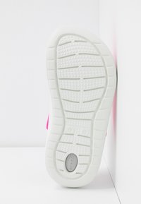 Semelle blanche avec un motif de grip texturé, présentant une section supérieure de couleur rose vif. Indique les marquages de taille sur la semelle.