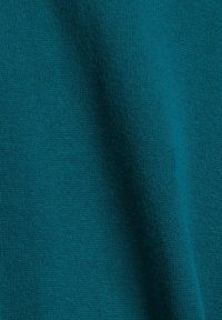 Gros plan d’un tissu sarcelle avec une texture fine en maille et une légère ombre créant un pli doux.