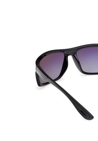 Černé sluneční brýle s gradientními fialovými skly. Elegantní design, ostrý tvar a hladký povrch. Obsahuje detail loga na nožičce.