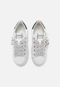 Zapatillas blancas con cordones de tela blanca texturizada, acento en el talón negro y cordones blancos gruesos con motas negras. Marca Karl Lagerfeld.