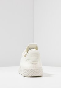 Vit sneaker med texturerad överdel, strukturerad häl och andningsbart mesh. Har en sula med rutmönster och en flik bak för enkel påtagning.