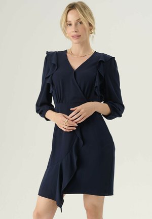 Navyblaues Wickelkleid aus glattem Stoff, mit Rüschensäumen, einem V-Ausschnitt und einem drapierten Rüschendetail am Rock.