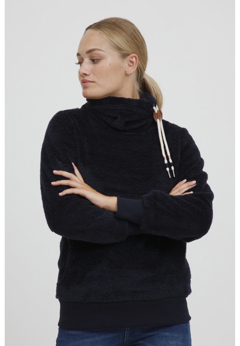 Pullover in pile navy con colletto alto, dotato di lacci decorativi e polsini a coste. Texture morbida con una vestibilità comoda.