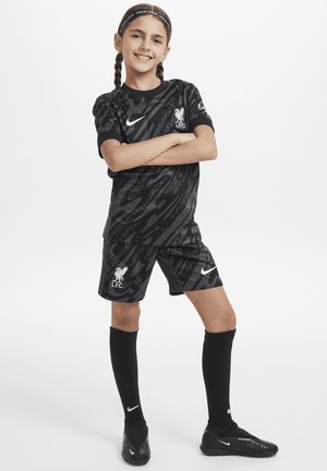 Zwart Liverpool FC jeugdvoetbalkit met een gestippeld shirt en shorts. Inclusief een wit Nike-logo en kniehoge zwarte sokken.