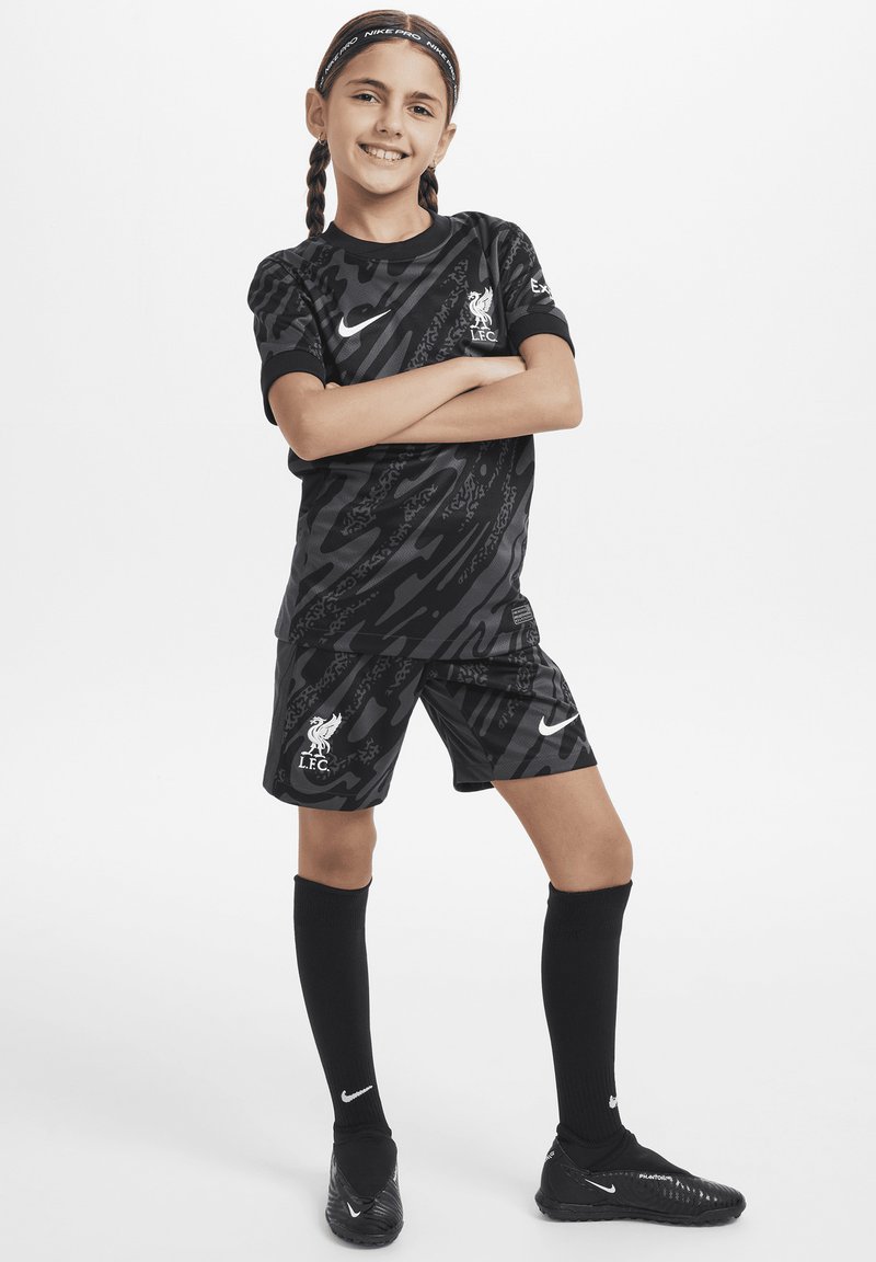 Ensemble de football pour jeunes de Liverpool FC en noir, comprenant un maillot à motifs et un short. Inclut un logo Nike blanc et des chaussettes noires montantes.