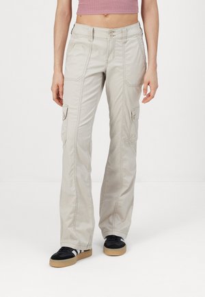 Pantalones cargo beige con un diseño de pierna recta, que cuentan con múltiples bolsillos, costuras en contraste y un cierre de doble botón.