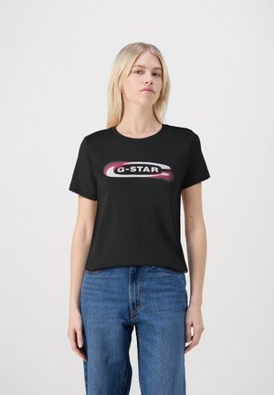 Schwarzes Baumwoll-T-Shirt mit einem runden G-Star-Logo in Weiß und Pink, klassischer Rundhals und kurzen Ärmeln, kombiniert mit blauen Jeans.
