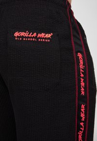 Zwarte textuurbroek met een taillezak en rode accenten, voorzien van de "Gorilla Wear Old School Series" branding aan de zijkant.
