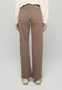 Brązowe dżinsy o szerokich nogawkach z wysokim stanem, z tkaninową metką skórzaną z tyłu, dwoma tylnymi kieszeniami oraz gładką, matową fakturą.