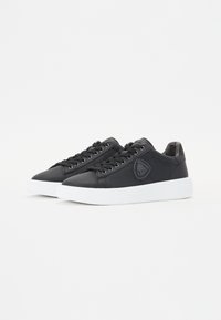 Mustad mustad nahksneakerid valge kummitald, ümmarguste šnörkide ja küljes oleva logoplaadiga. Sile tekstuur, madal disain.