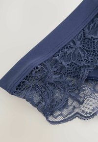 Mörkblå spetsunderkläder med en slät midjeband och intrikata blommönster i spets, med en scalloped kant längst ner.