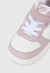 Nike tenisice s gornjim dijelom od mekog lavande kože, bijelim sintetičkim vrhom i vezanjem. Teksturirana potplat s perforacijama za prozračnost.
