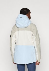 Kerge, kapuutsiga jakk, millel on värviplokkilahendus. Koosneb beežist, valgest ja helesinisest osast ning sellel on tõmblukuga tasku varrukal. Sujuv tekstuur.