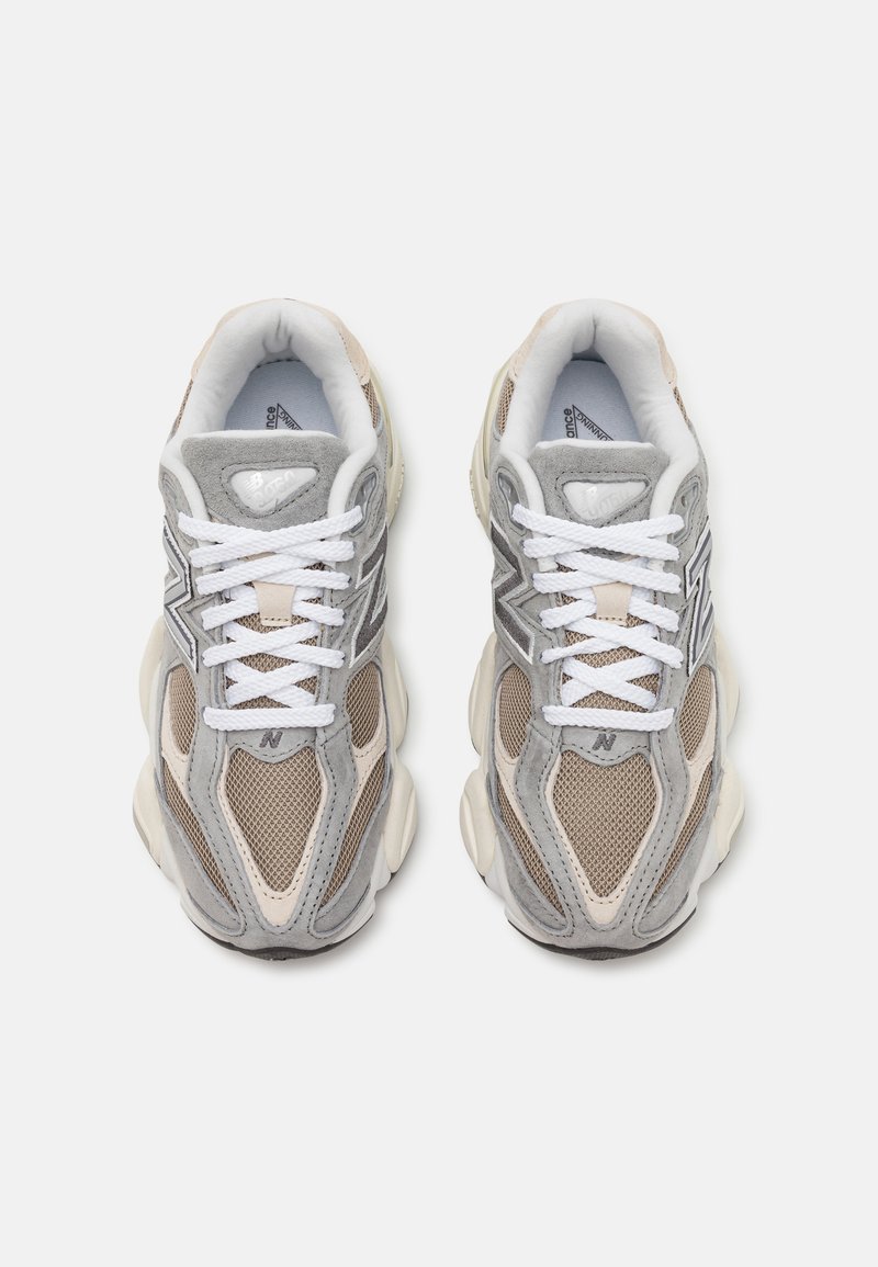 Baskets de sport grises et beiges avec un dessus en mesh, des accents en daim, de larges lacets blancs et un design de semelle épaisse.