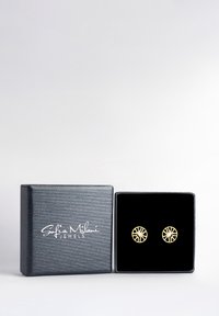 Guldpläterade örhängen med en cirkulär design, försedd med ett utstansat mönster och en central kristall, visade i en låda klädd med svart sammet.