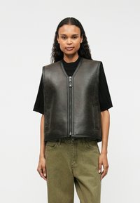 Zwarte leren vest met een rits aan de voorkant, ronde halslijn en twee zijzakken, gecombineerd met een olijfgroene onderkant. Soepele textuur, minimalistisch ontwerp.